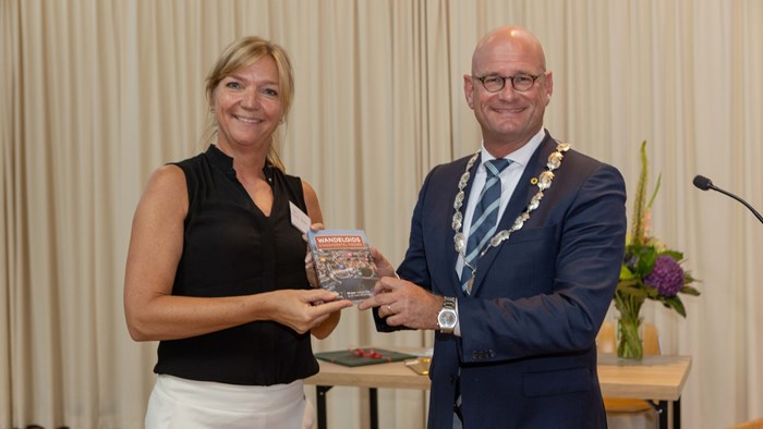 Burgemeester Jan Nieuwenburg krijgt van bestuurslid Stadsherstel Hoorn Nancy Alders het eerste exemplaar van de wandelgids uitgereikt